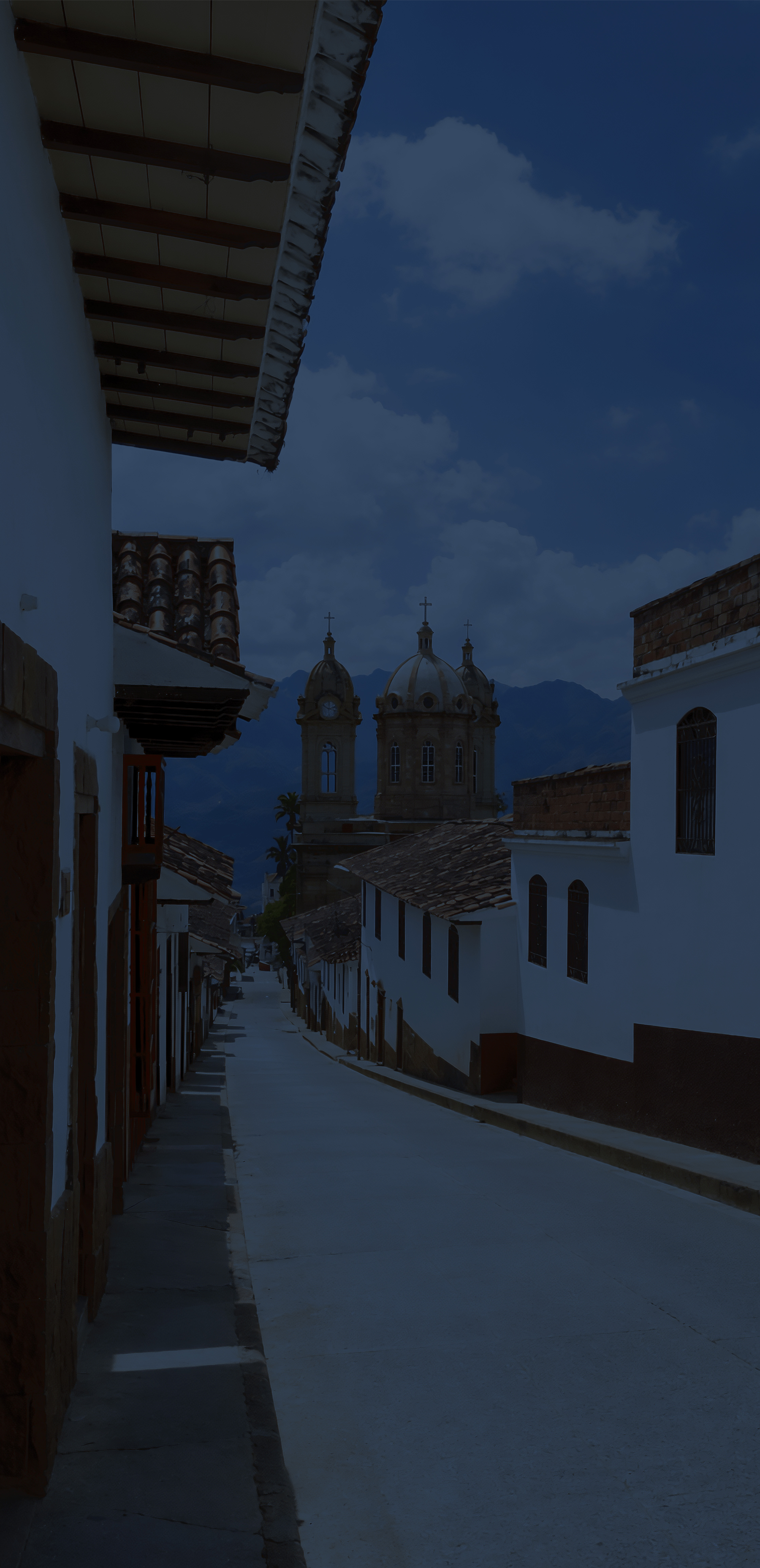 Calle colonial estrecha con balcones de colores.